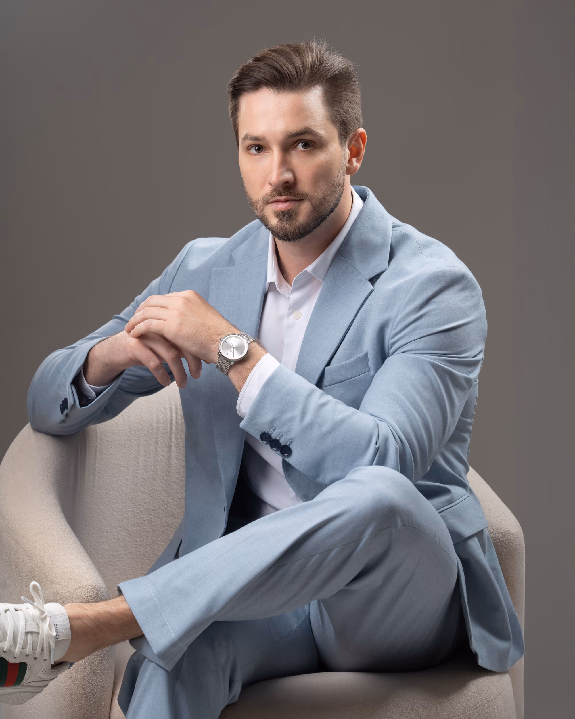 Dr. Felipe Hell Andrade sentado em uma poltrona, de terno azul-claro